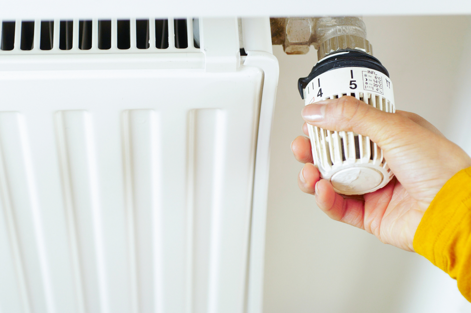En kvinne som endrer temperaturen på radiatoren